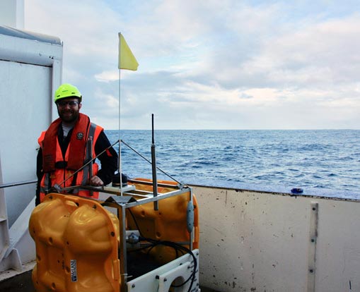 Ryan Yohler posing next to equipment on a ship