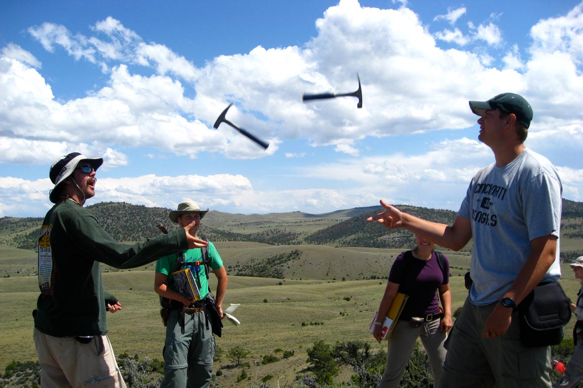 Two students tossing hammers to one another