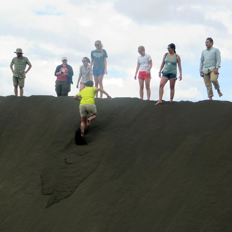 Student running up a steep ridge as others look on