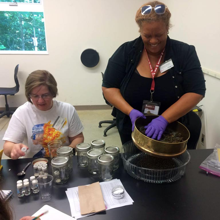 Two women handling a variety of equipment for a scientific experiment