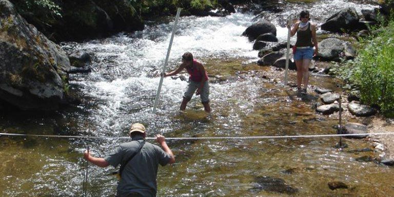 Three people wading in a river