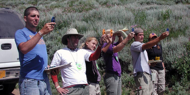 Group of students using handheld technology to perform research in the field